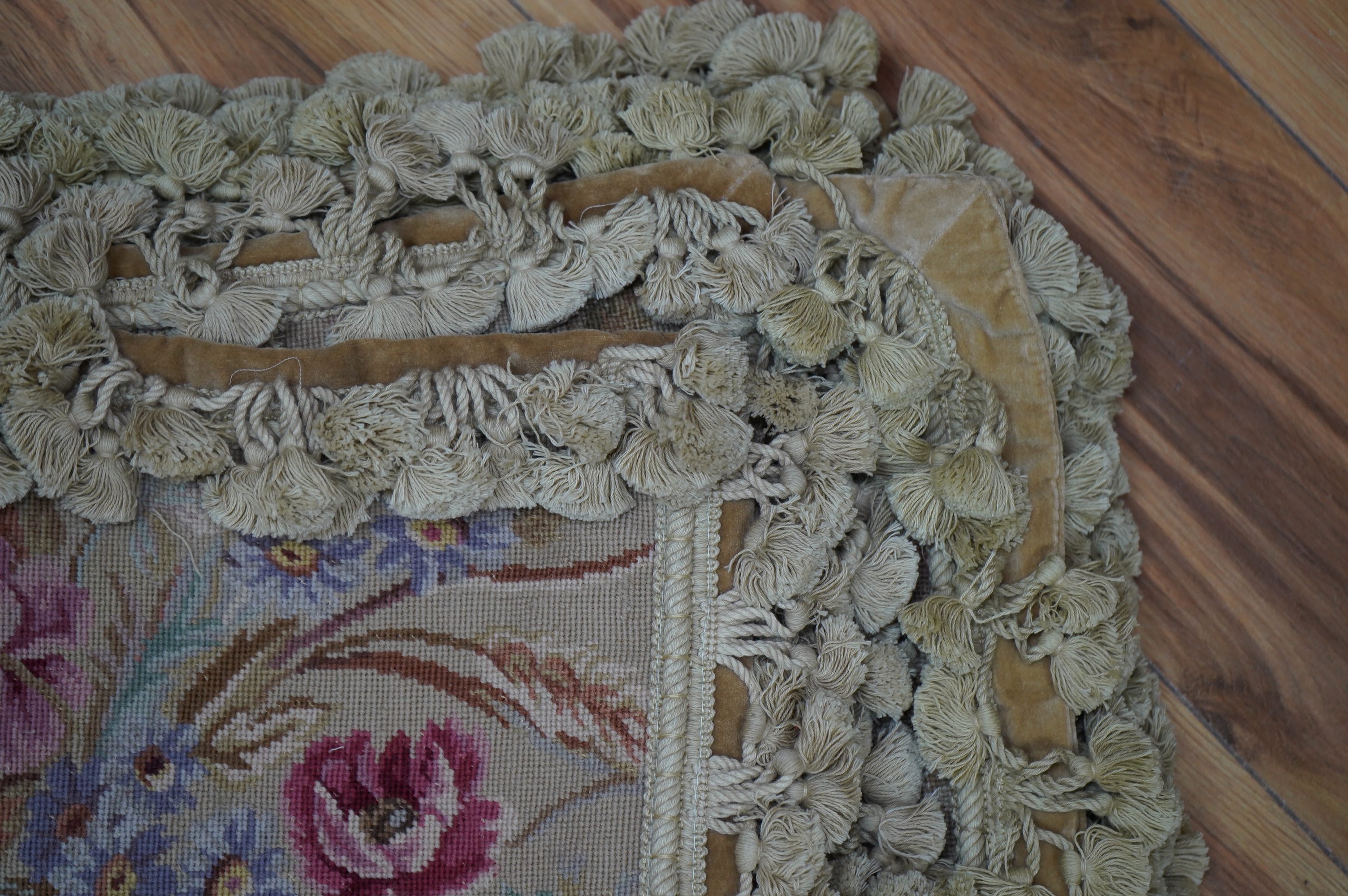 Four rectangular pink roses patterned wool worked cushions, all with mushroom tasselling, largest 46cm wide, 34cm high. Condition - good